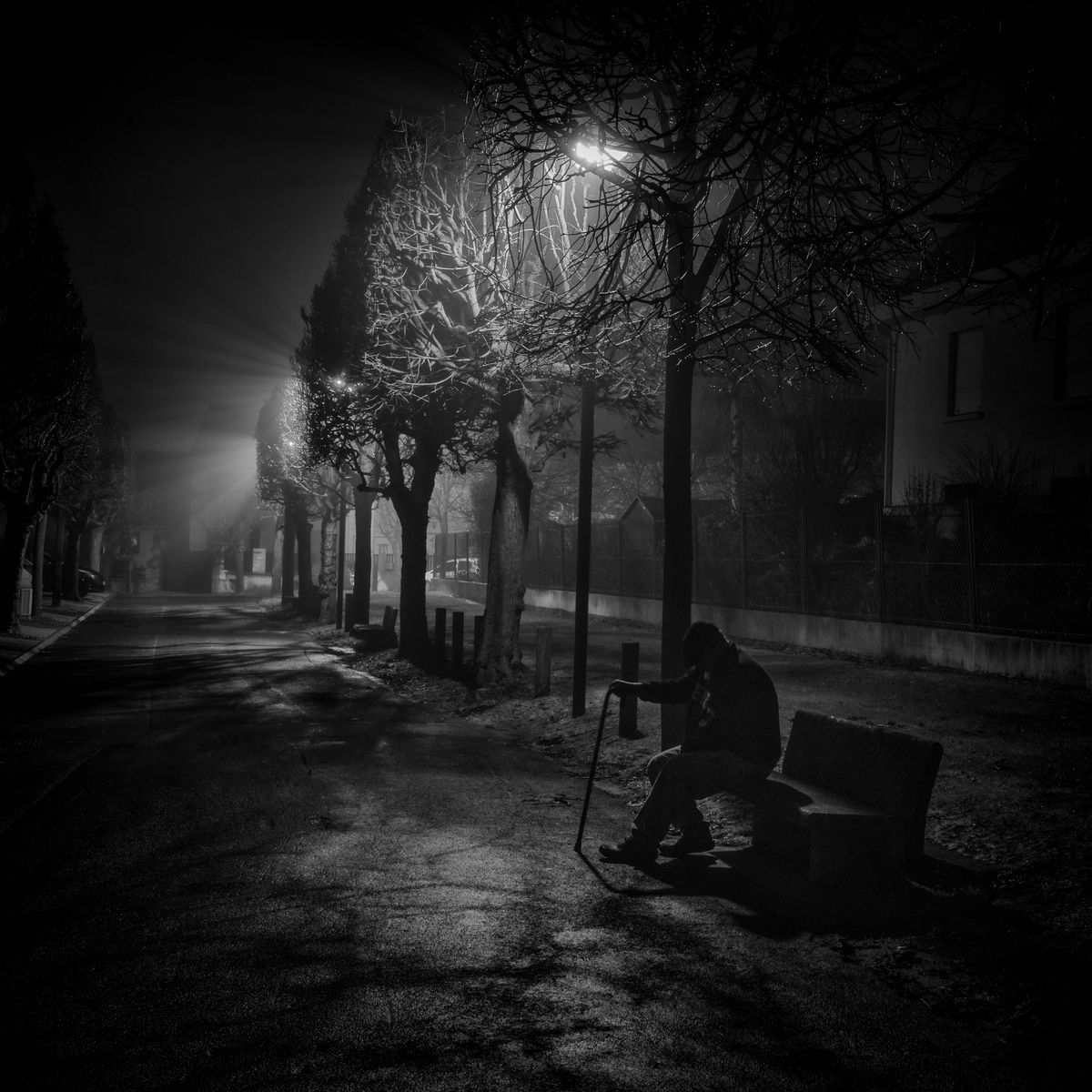 En banlieu de Paris un vieil est assis sur un banc près d'un cimetière